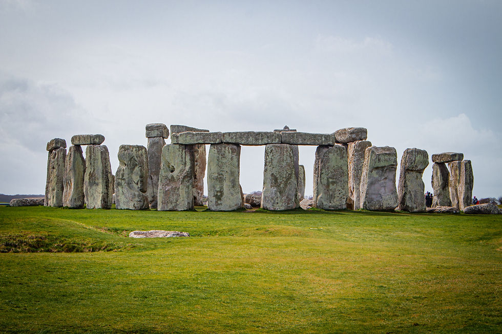 Stonehenge under cloudy skies, ancient stone circle on green grass, no visible people, focusing on the massive weathered rocks.