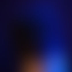 Close-up of a microphone illuminated by blue light against a dark background, highlighting its mesh pattern and metallic details.