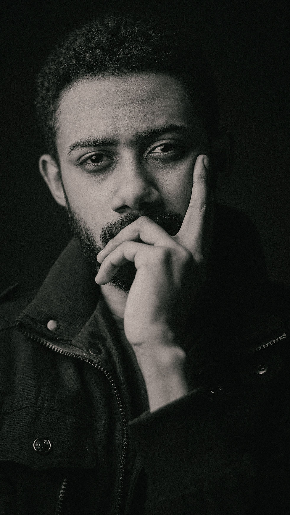 Bearded man resting his chin on his hand looking deep in thought