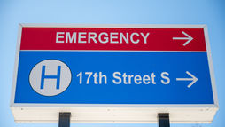 Sign pointing to the emergency department and 17th Street S under a clear blue sky, symbolizing the direction and readiness of an emergency nurse in critical situations.
