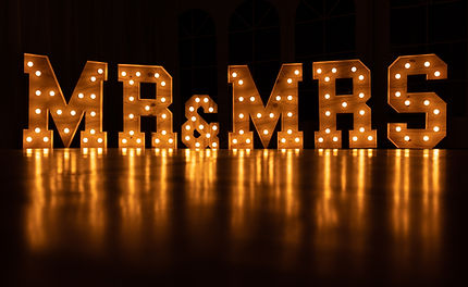 Large illuminated "Mr and Mrs" letters glowing softly at wedding venue