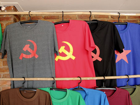 Bursa toptan giyim mağazasında askıda farklı renklerde ve baskılı tişört modelleri – erkek ve unisex koleksiyon.