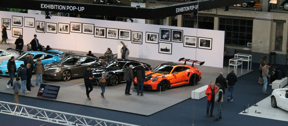 Exhibition pop-up event with luxury sports cars on display and attendees viewing a gallery wall, illustrating in-person brand activation.