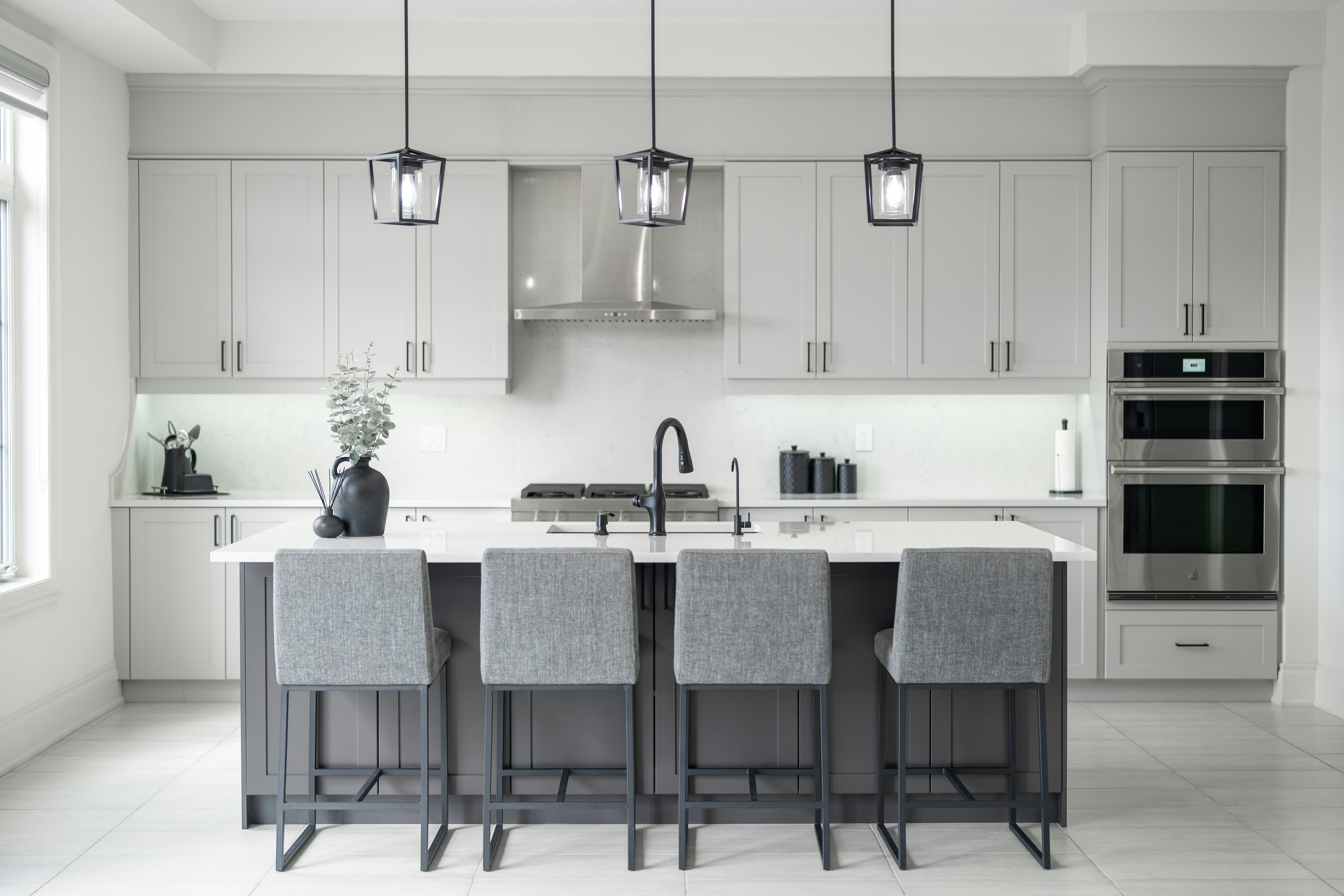 Moderna cocina con isla, taburetes y campana extractora.