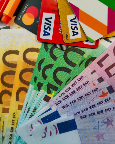 Euro banknotes and credit cards fanned out on a table.