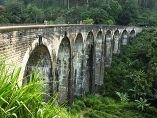 Stone bridge stretching across a dense green forest, symbolizing stability under pressure.