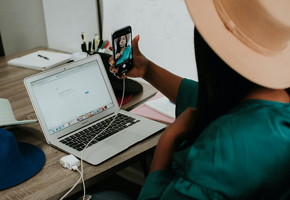 Woman working on her laptop and recorning herself on her cell phone