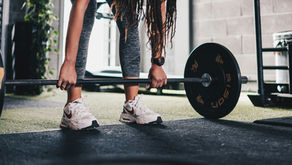 woman with braided hair getting ready to lift a barbell in gym