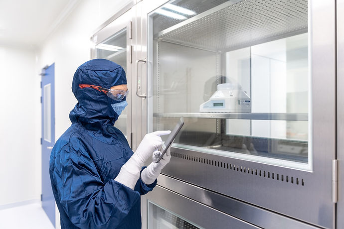 Technician in cleanroom gear reviewing batch data on a tablet
