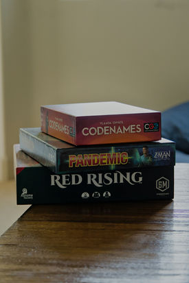 Pile de jeux de société Codenames, Root et Red Rising.