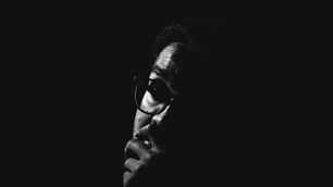 A black and white image of a man staring into darkness.