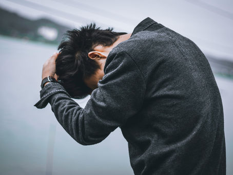 Man holding his head with a distressed and overwhelmed expression, representing stress, anxiety, emotional exhaustion, burnout, and mental health struggles.
