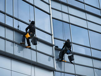 Zwei Menschen reinigen eine Glasfassade