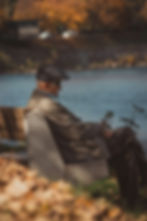 An old gentleman in a flat cap sitting on a bench by water, like Theo of Golden.