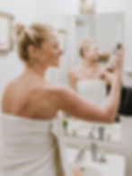 woman in bathroom holding face spray