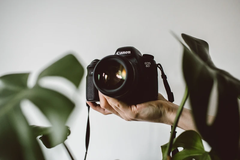 a hand is holding a canon dslr camera