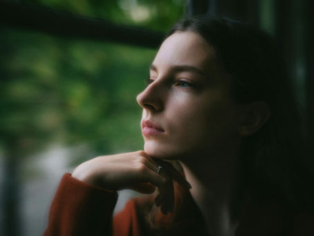 Nachdenkliche Frau blickt in die Ferne, ruhiger natürlicher Hintergrund