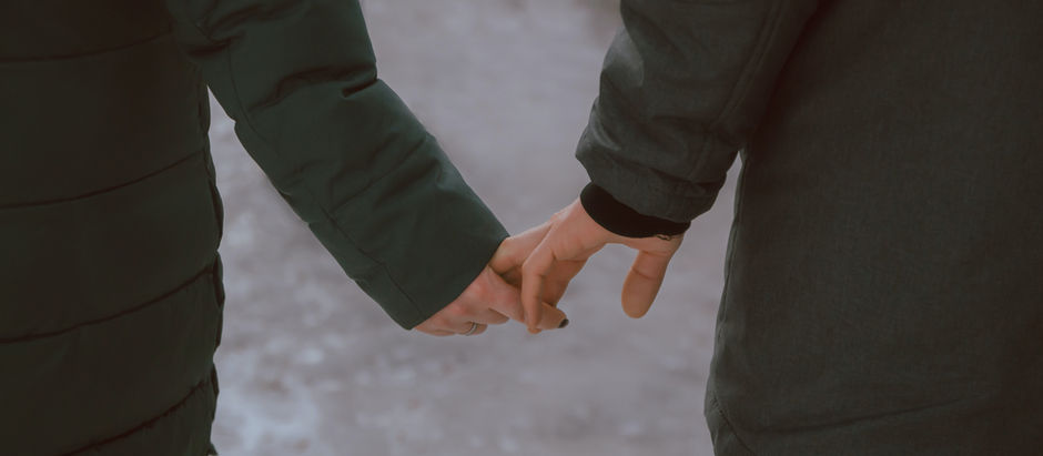Two people reaching out and trying to hold each other’s hands, their fingers barely touching, symbolizing the struggle of letting go in a relationship.