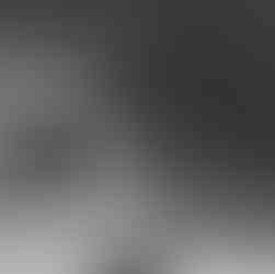 Dramatic black and white photograph of a stone church bell tower topped with a cross in Nazareth.