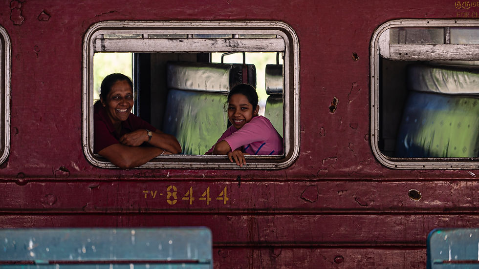 Two women smiling through a train window in Sri Lanka.