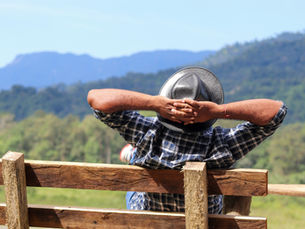 Man sat on a bench with his hands behind his head looking out at the rolling hills
