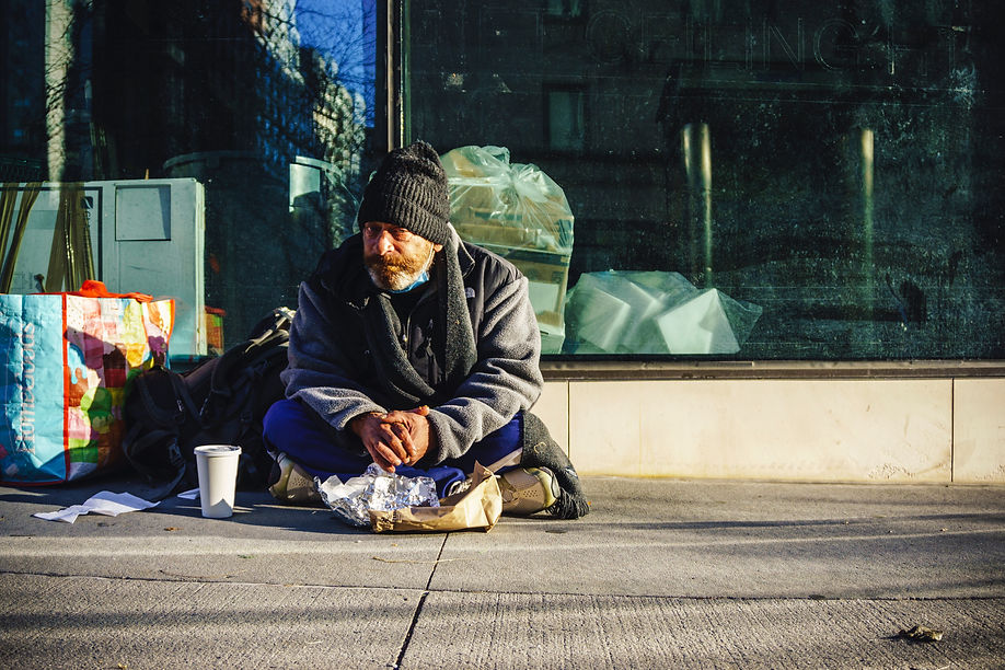 Homeless man sitting on sidewalk