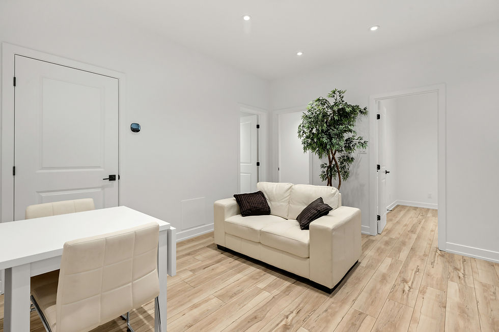 Bright modern white room with a cream sofa, dining table, chairs, potted tree, and open doors on wood floors.
