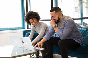 2 people smiling and looking at laptop