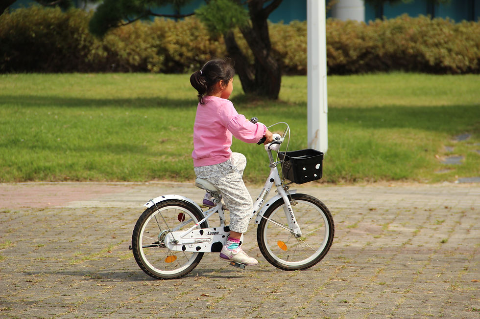 Petite fille qui fait du vélo près d'un parc