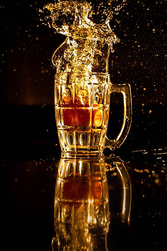 glass of beer splashing on a black background