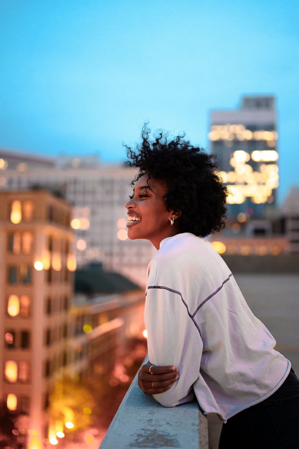 Black woman standing on a balcony smiling over a city