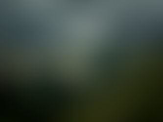 mountains speckled with snow and clouds with green hills and pines in front of it.
