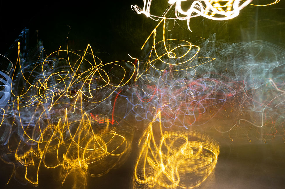 Swirling golden, white, and red light trails on a dark background create an abstract, energetic pattern.