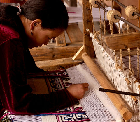 Rug weaver weaving a rug on a loom.