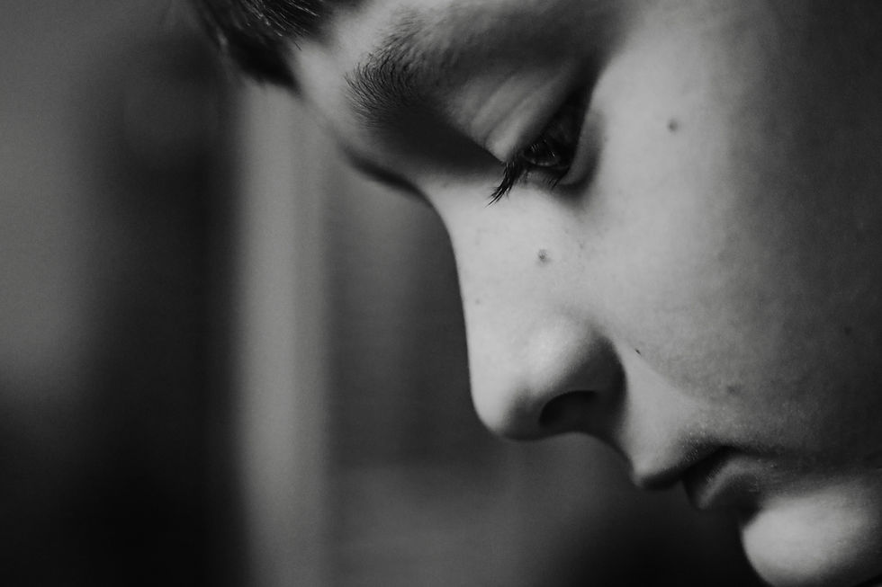 Close-up of a child's face in profile, looking down in a contemplative mood. The black and white image highlights subtle details and shadows.