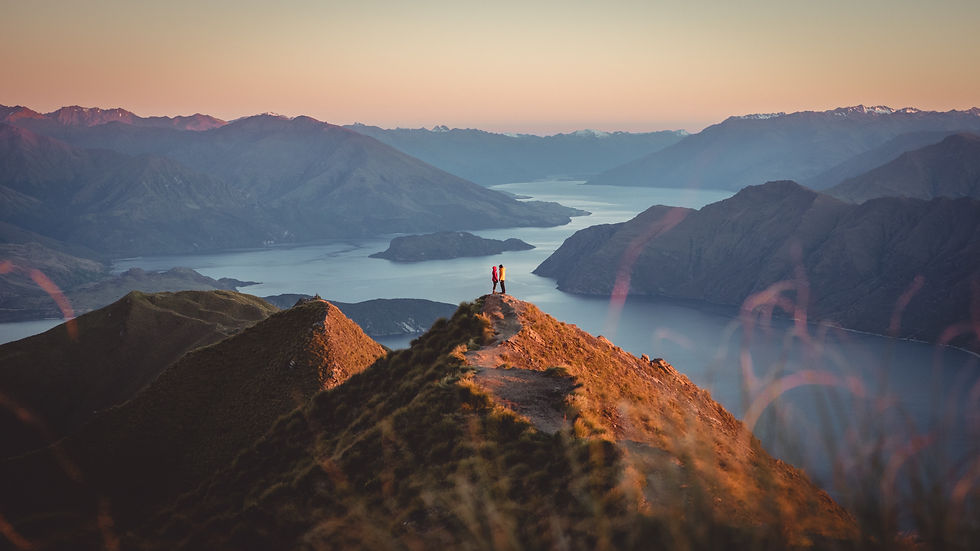 Couple standing on Roys Peak overlooking Lake Wanaka and the Southern Alps, New Zealand