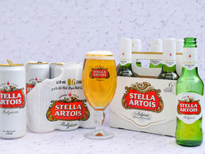 A display of Stella Artois showcases a glass of its signature golden lager, surrounded by bottles and cans highlighting its Belgian brewing heritage.