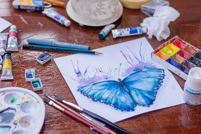 Butterfly art on a desk with art supplies