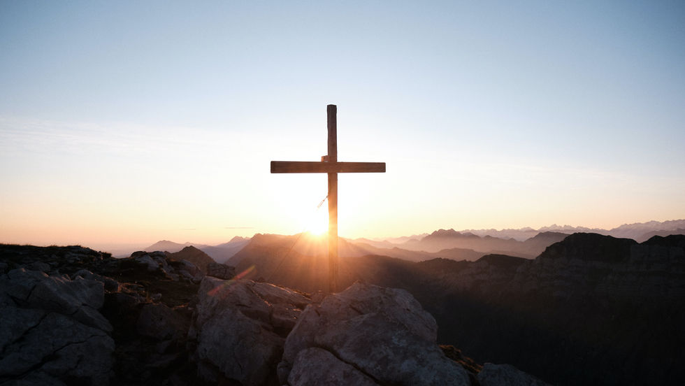 Christian Cross with sun rising in behind it.