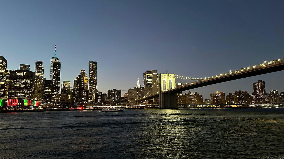 The illuminated Brooklyn Bridge and Manhattan skyline reflected on the East River in New York City. Nighttime cityscape with