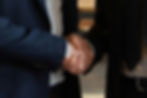 this is an image of a handshake. two gentlemen giving a firm handshake, they appear well dressed both in suits and dress shirts. but not much else can be said as there is nothing to distinguishing in the image.