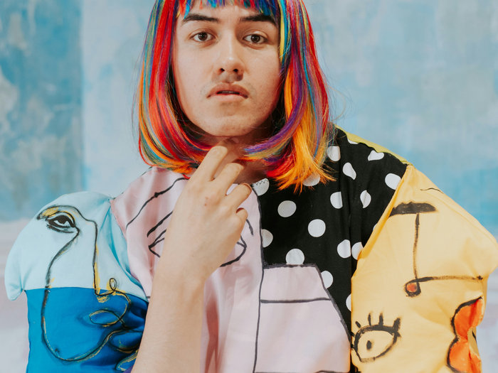 Person with rainbow hair wearing a colourful patterned jacket