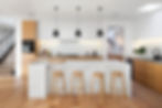 Modern kitchen with white countertops and wood barstools.