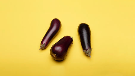 Three eggplants on yellow backdrop