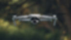 A gray drone labeled "Air 2S" hovers mid-air with propellers spinning. The background is blurred greenery, creating a serene outdoor setting.