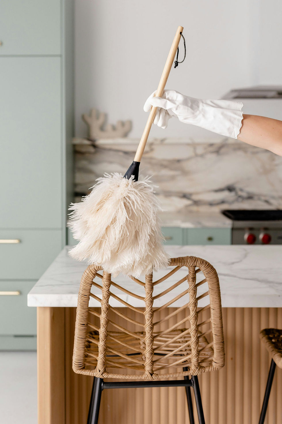 Gloved hand dusting with a feather duster for house cleaning services