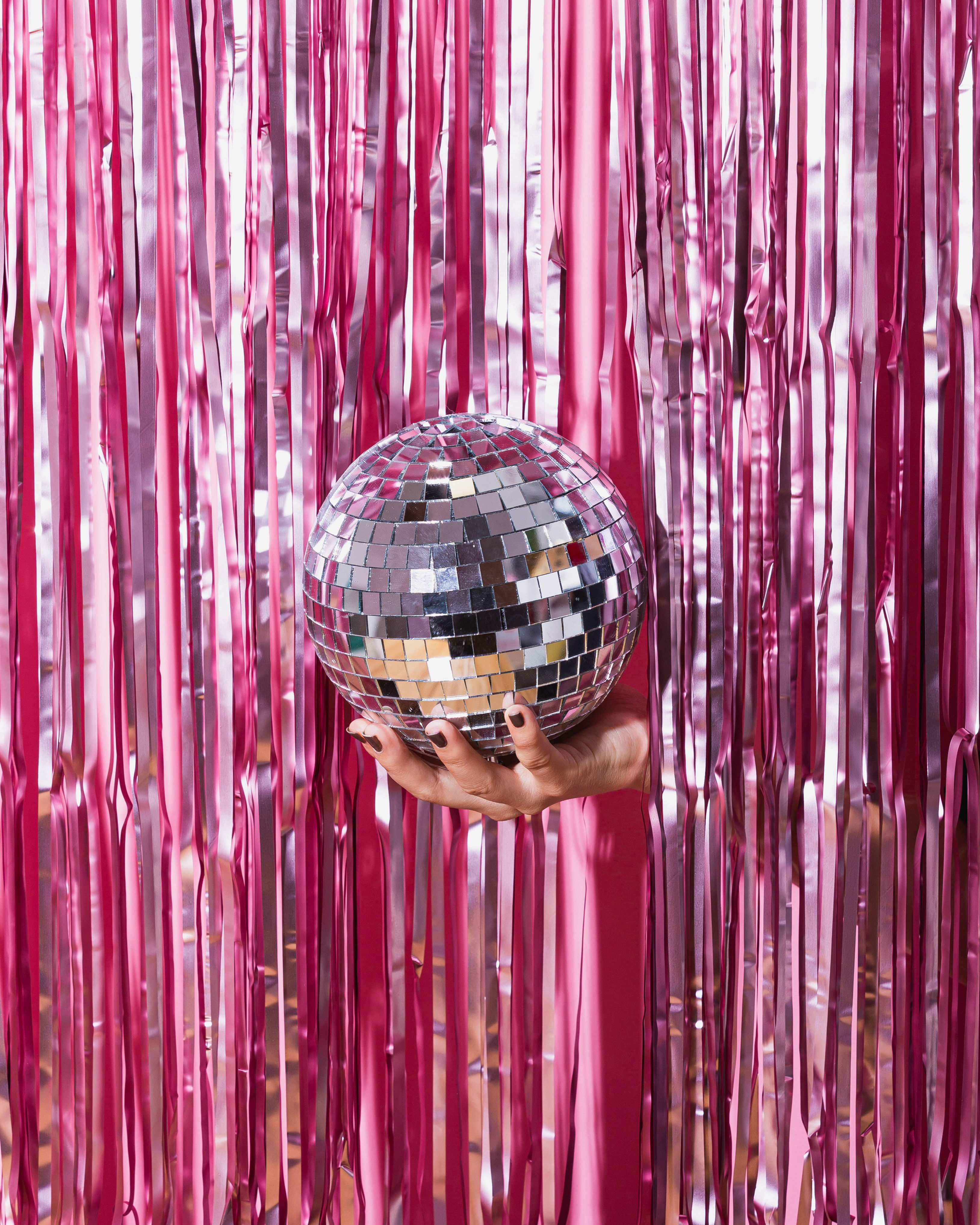 A pink shiny curtain with a silver disco ball