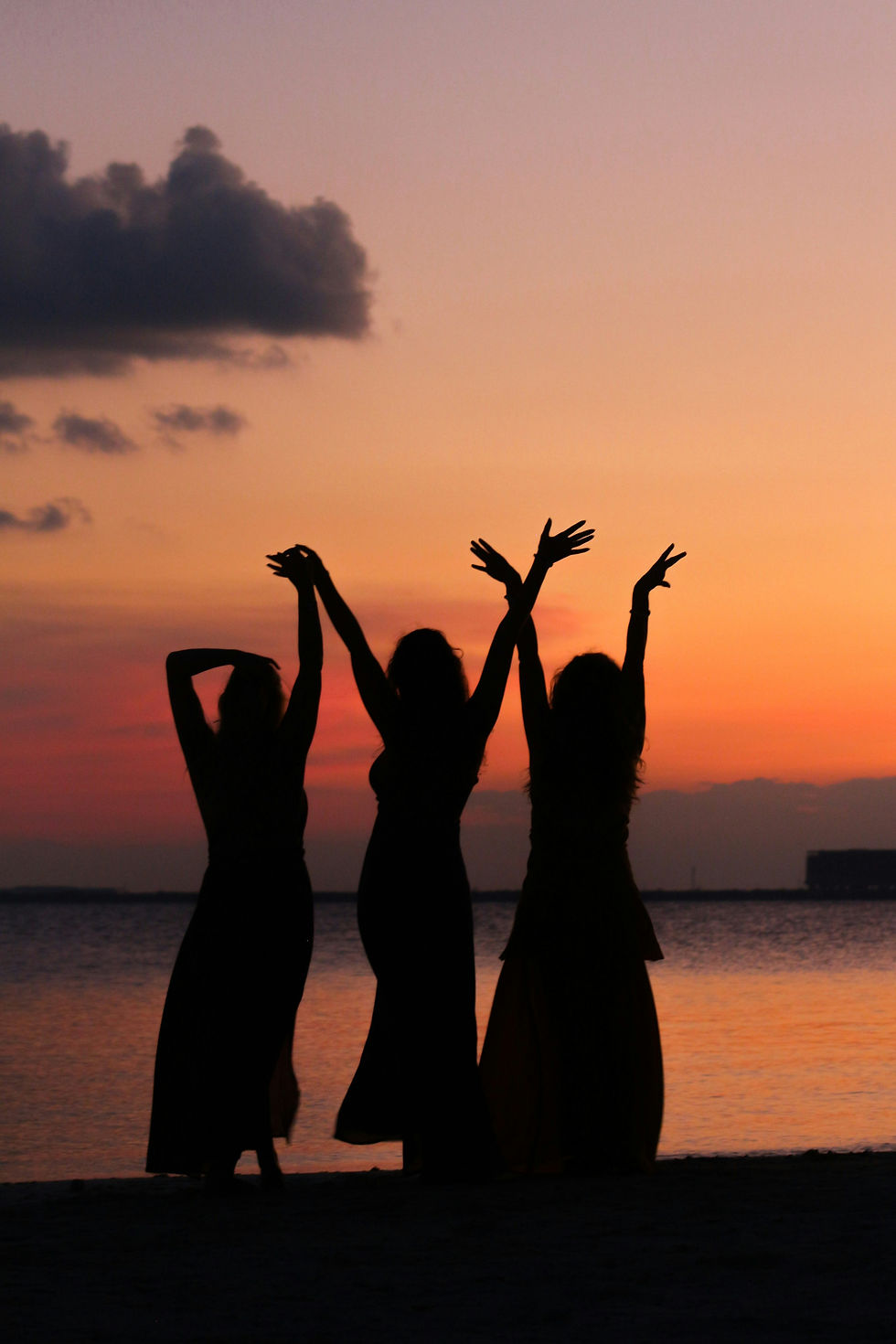 Three girls celebrating in front of a sunset