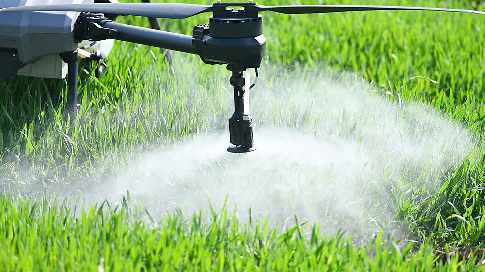 Drone spraying mist over lush green grass in a field, creating a foggy effect. The scene is bright and vibrant with a focus on agriculture.