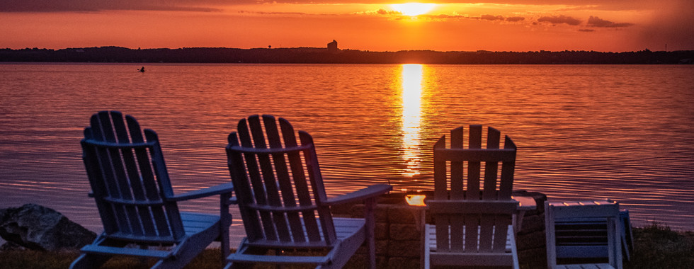 Sunset over Grand Traverse Bay with Adirondack chairs in Traverse City, Michigan.